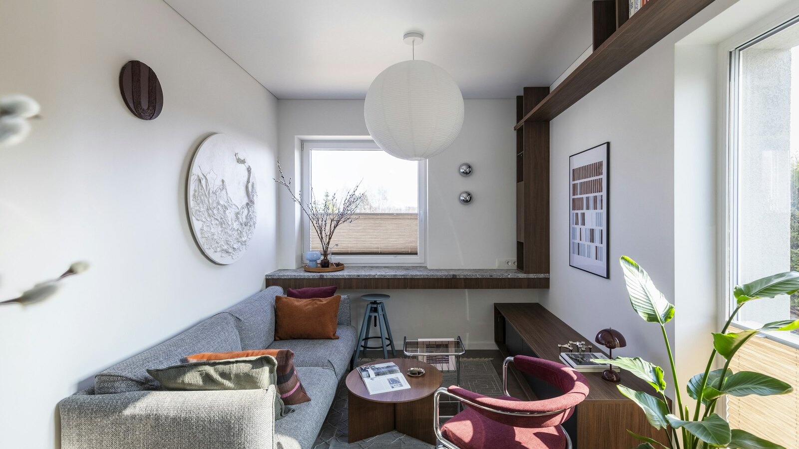 A calm room with a soft chair, books and plants by a window