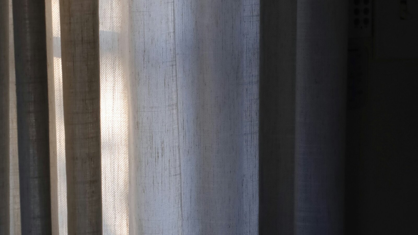 Soft sunlight through a linen curtain in a quiet room